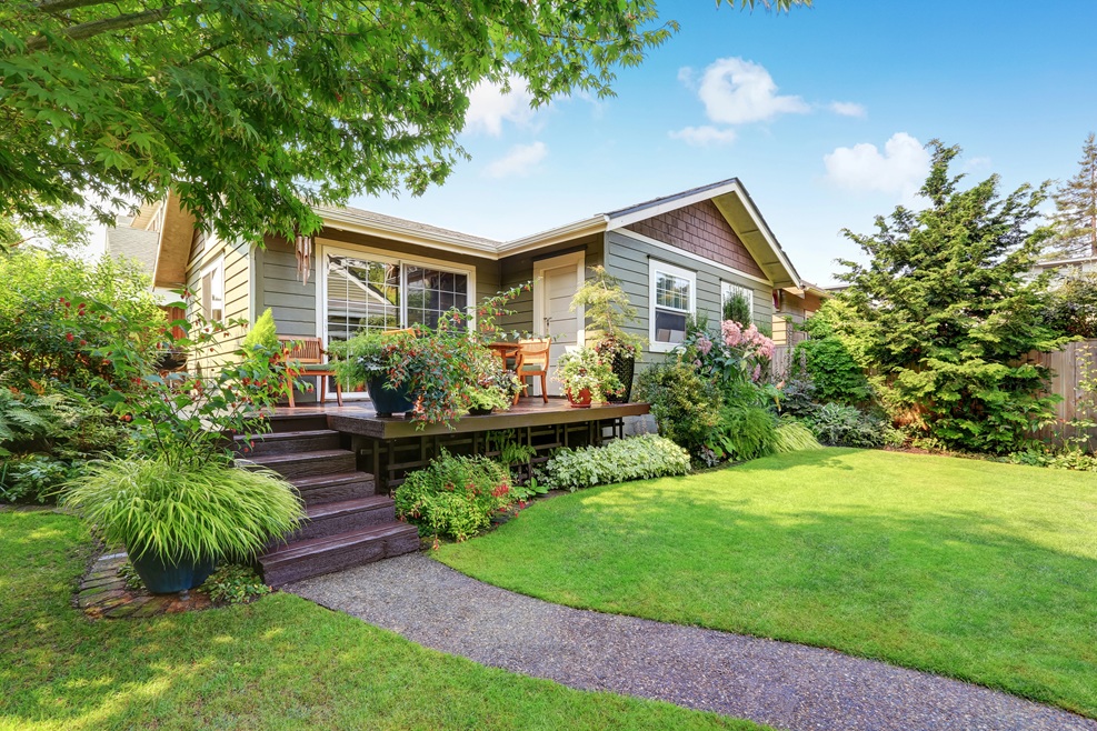 Beautiful single-story home with a raised wooden deck surrounded by lush landscaping, representing an example of a backyard space suitable for an attached or detached ADU in Raleigh or Cary, North Carolina.