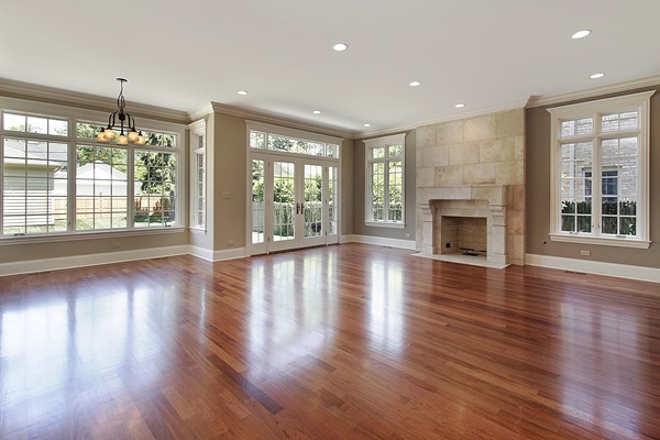 High-end expanded living room with hardwood floors, stone fireplace, and large windows—part of a $1M+ luxury home addition in Raleigh built by Jeff Wiblitzhouser of Paradise Found Construction.