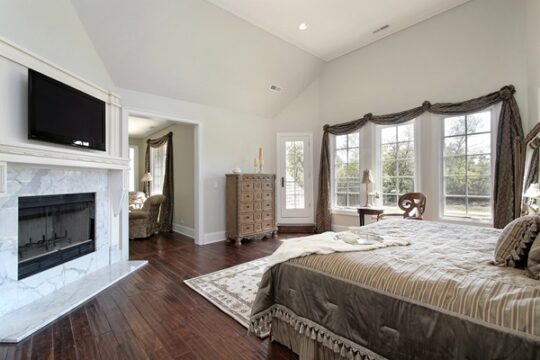 Luxury master bedroom suite with hardwood floors, marble fireplace, and natural light—part of a $1.2M+ home addition designed by Jeff Wiblitzhouser, expert builder at Paradise Found Construction.